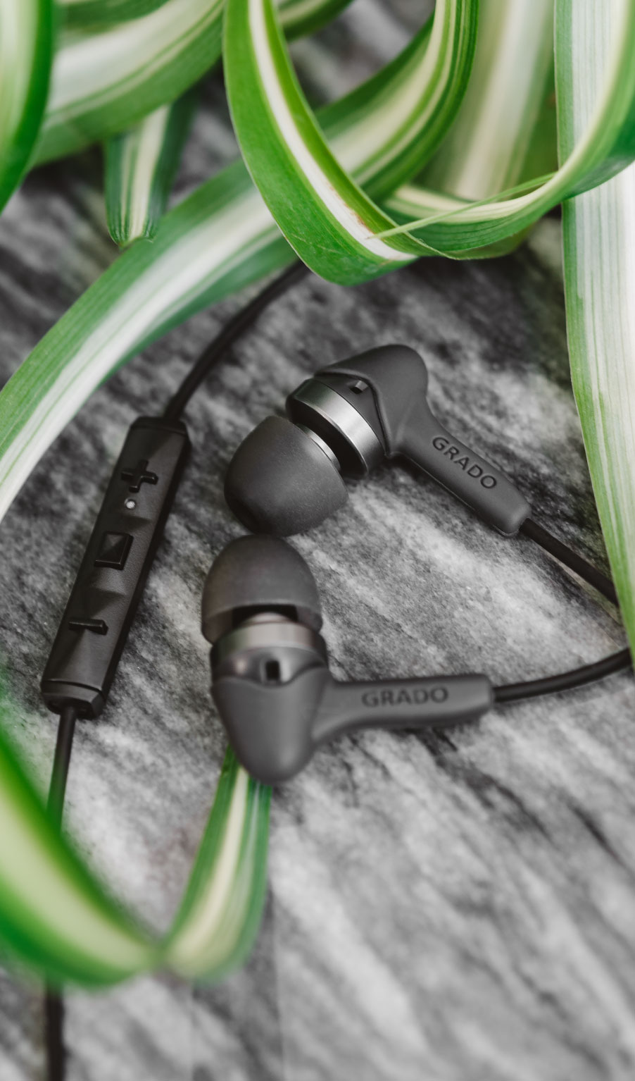 Photo of grado ige3 headphones on a grey table with green plant leaves in the foreground