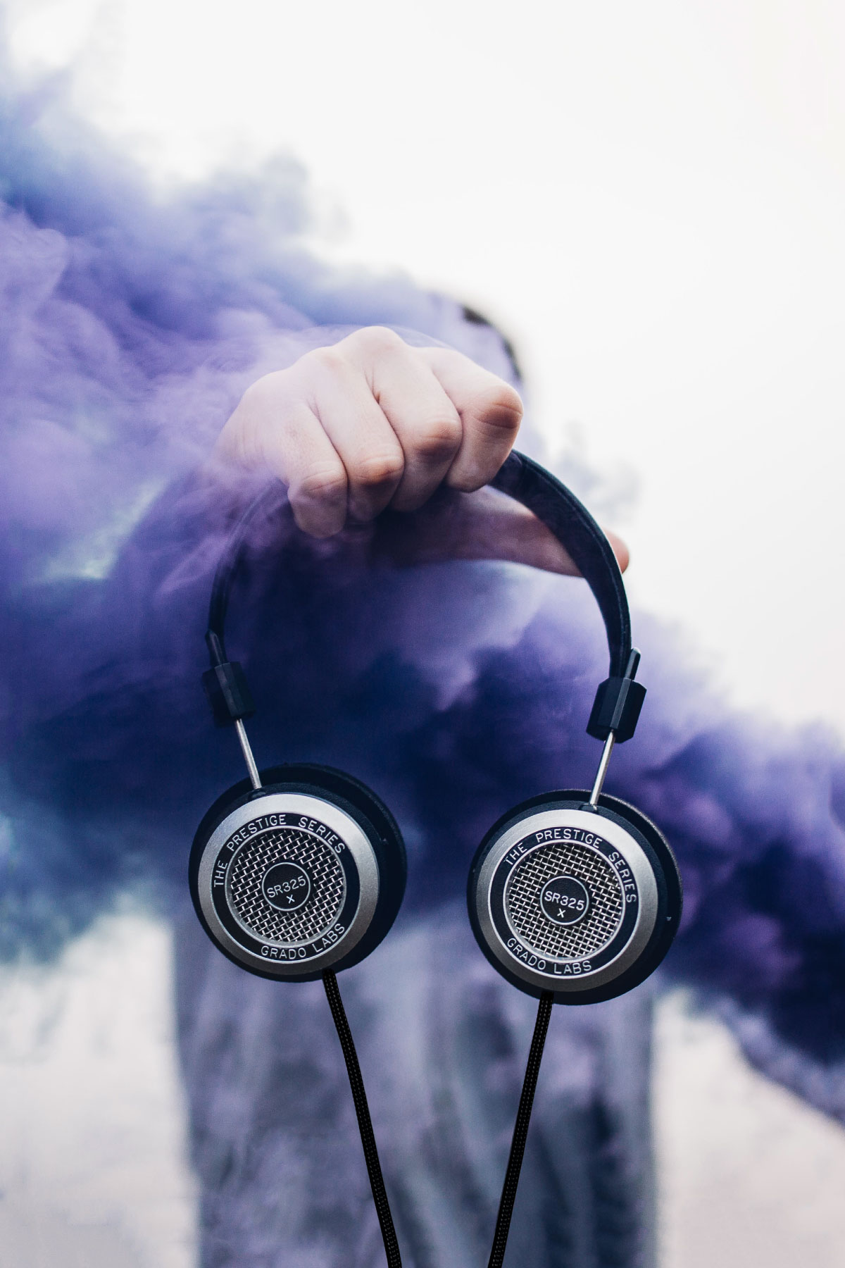 Photo of a person holding the sr325x headphones, surrounded by purple smoke.