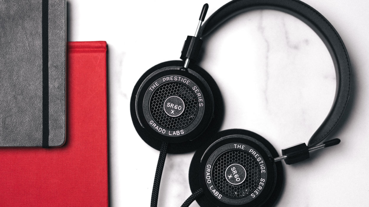 Photo of SR60x headphones taken from above showing the headphones on a white marble table next to a closed red book and a closed grey book