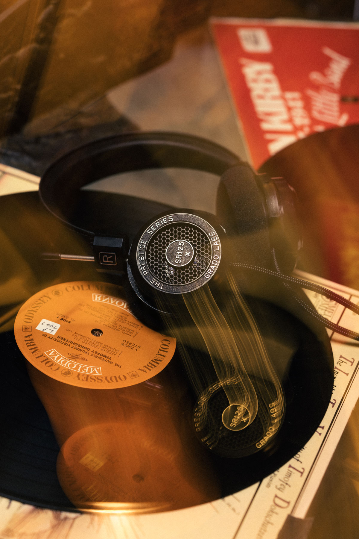 Photo of SR125x Headphones sitting on top of a record which is on top of it's sleeve with light trails.