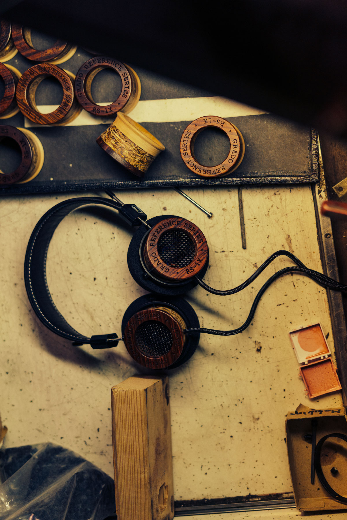 Photo taken from above of RS1 Headphones resting on a wooden workbench next to parts for the RS1 Headphone.